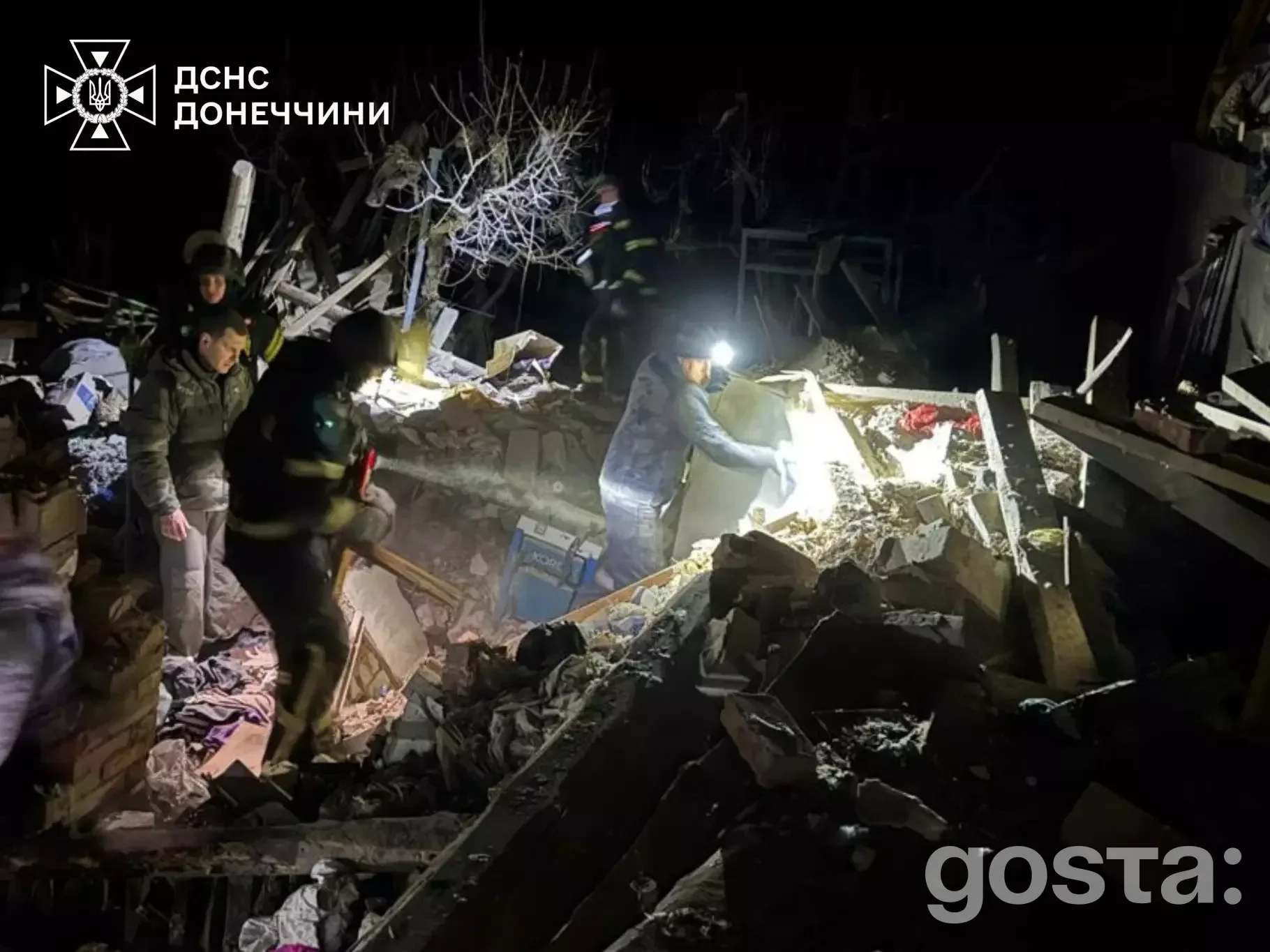 Рятувальники працюють на місці обстрілу в Донецькій області, 13 лютого 2026, зруйновані будівлі та нічний пейзаж.
