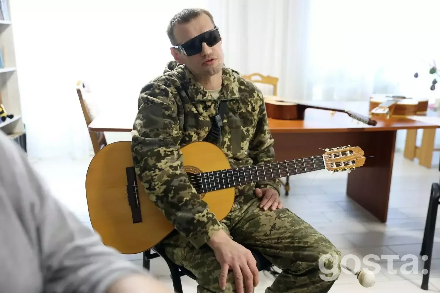 Військовий у камуфляжі грає на гітарі, реабілітація ветеранів у центрі «Пуща-Водиця», програма «Перезавантаження 2.0».