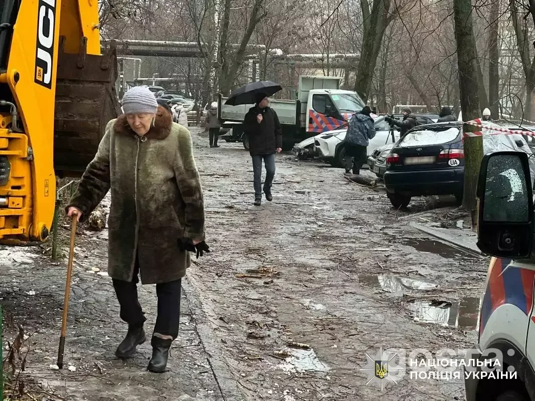 Elderly woman walks past damaged cars and debris in Dnipro after a Russian attack, highlighting the human impact of conf