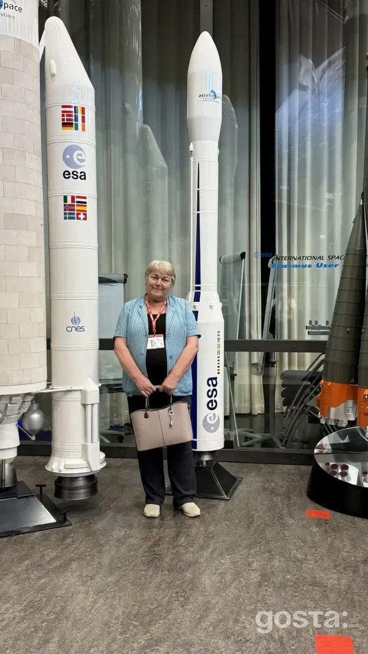 Науковиця Даша Добричева на фоні ракет ESA та CNES на виставці про нові галактики з полярними кільцями.