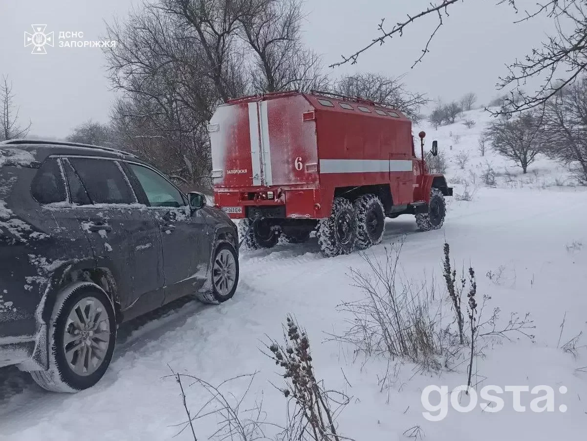 Рятувальники ДСНС України на сніговій дорозі з пожежним автомобілем під час зимових умов у сільській місцевості.