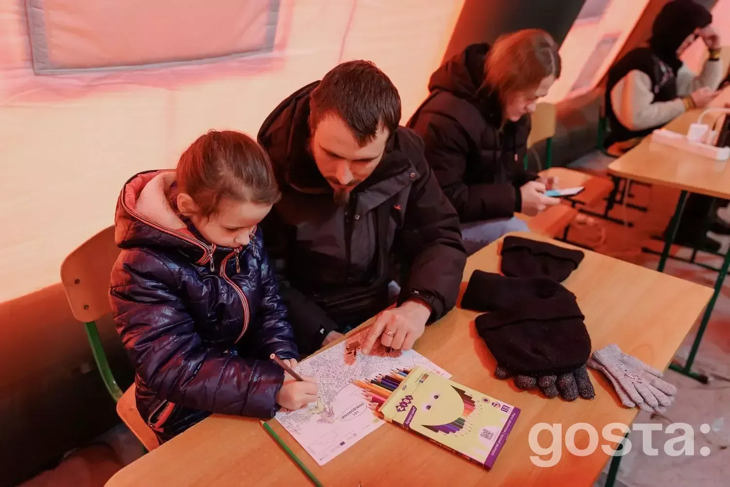 Дорослий і дитина розфарбовують у центрі підтримки під час надзвичайної ситуації в Україні.