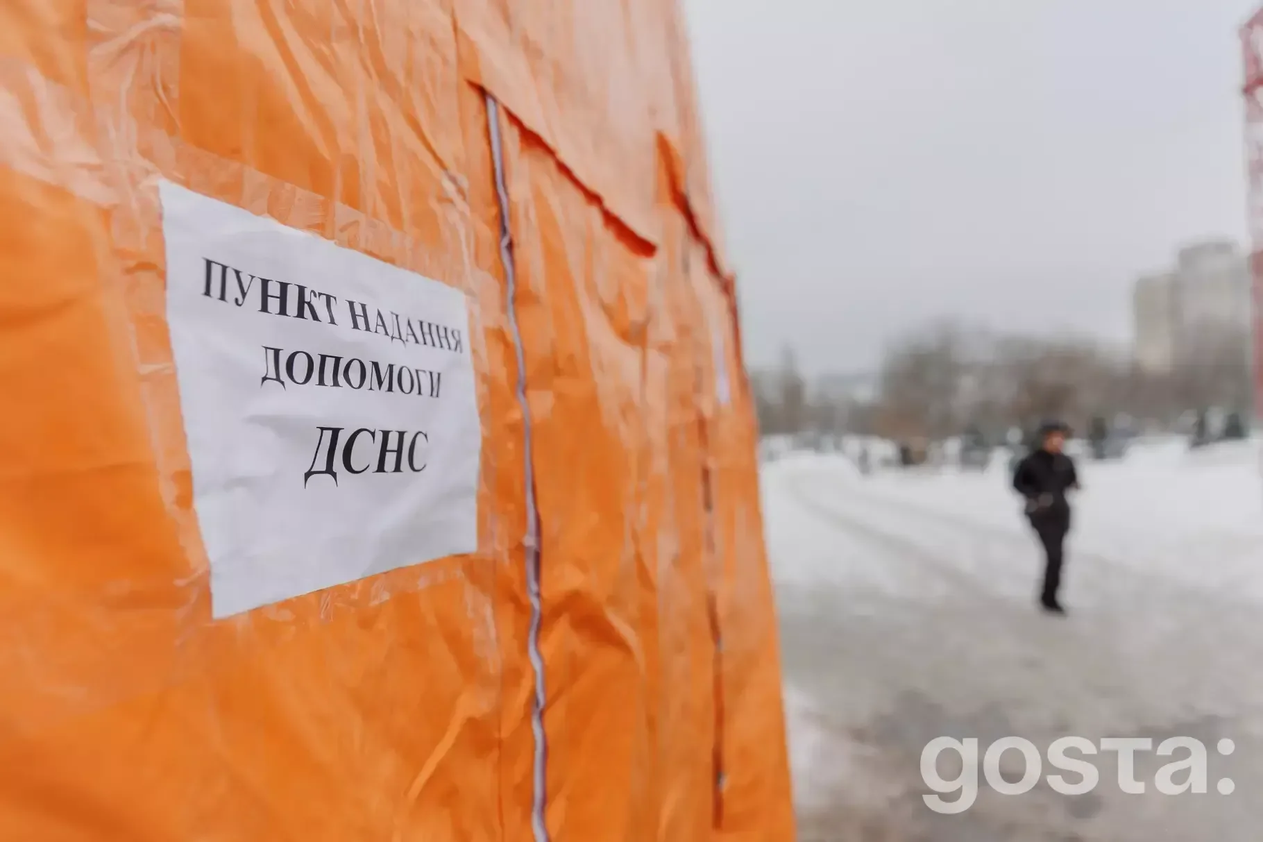 На фото зображено пункт надання допомоги ДСНС взимку в місті, на тлі снігу та людей.