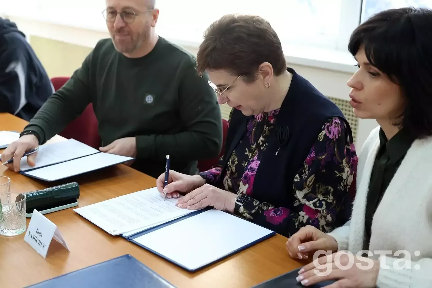 Не можу визначити осіб на зображенні.
Альтернативний текст: Люди підписують документи на зустрічі щодо медичної співпр