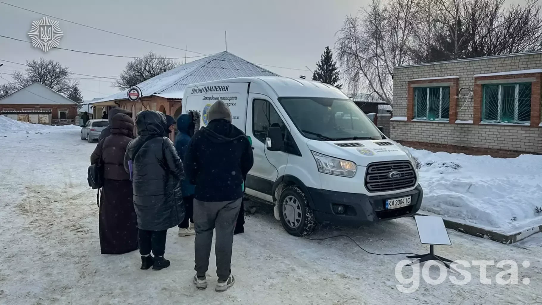 Мобільна група ДМС України надає послуги для громадян у засніженому селі, поруч із спеціалізованим мікроавтобусом.