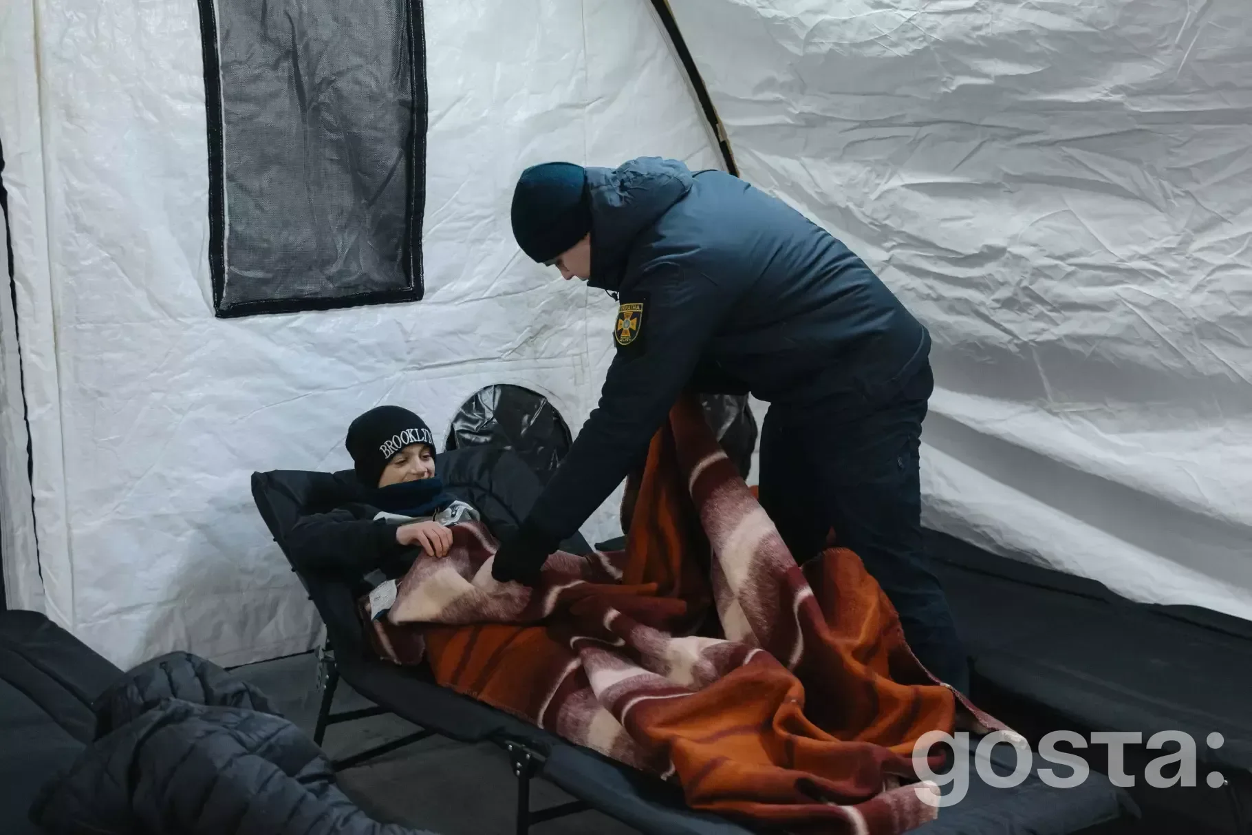 Укриття ДСНС у Києві: рятувальник накриває дитину ковдрою в пункті обігріву під час енергетичної кризи.