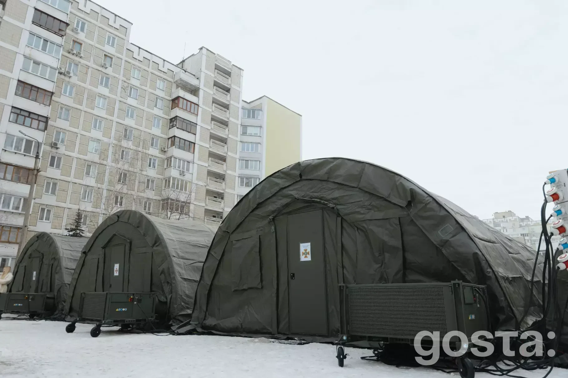 Три намети ДСНС для обігріву на засніженій вулиці Києва, поруч багатоповерхівки, зима, січень.