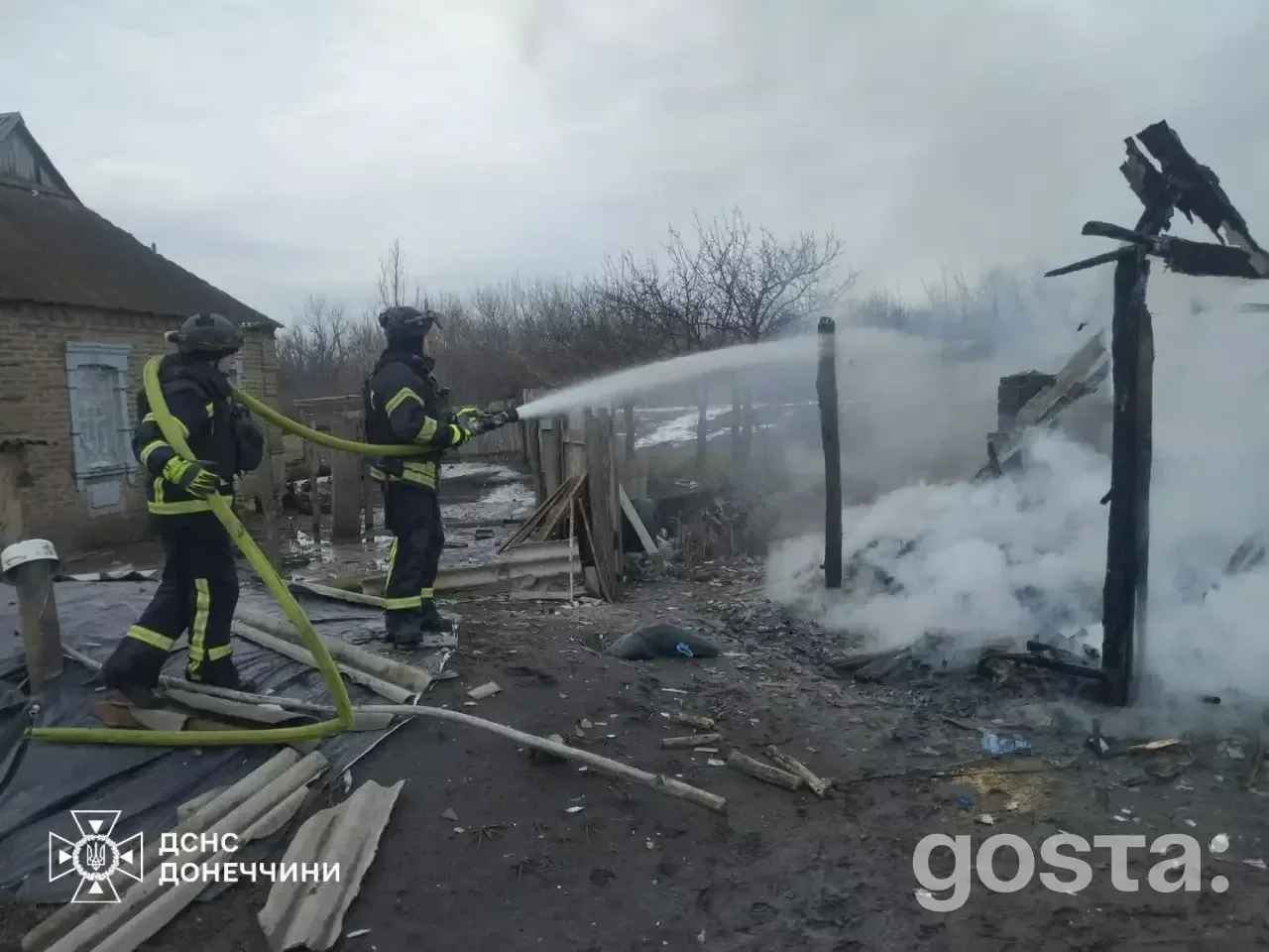 На зображенні пожежники гасять залишки зруйнованої будівлі під час відновлювальних робіт в Україні після обстрілу.