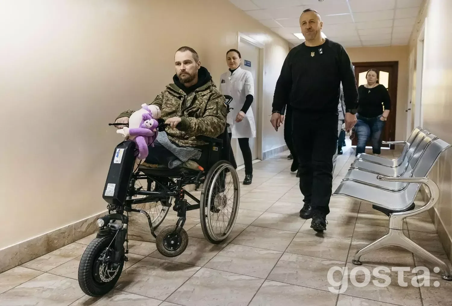 Чоловік у інвалідному візку з електроприводом у медичному центрі, переваги реабілітації з новітніми технологіями.
