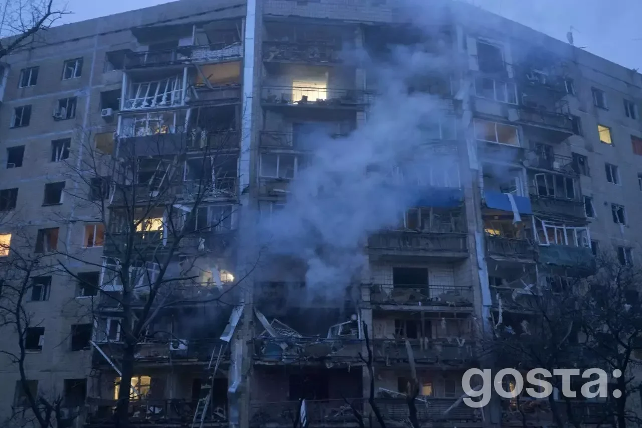Житловий будинок в Україні зазнав руйнувань від обстрілів, дим підіймається з вікон, видно значні пошкодження фасаду.
