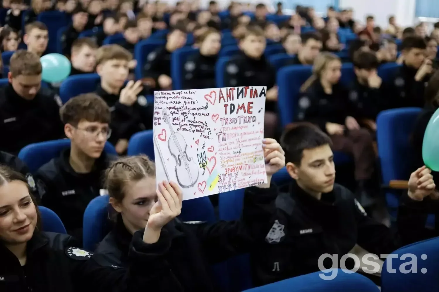 Ліцеїсти у формі слухають виступ гурту «Антитіла» в Івано-Франківську, тримаючи плакат зі словами підтримки.