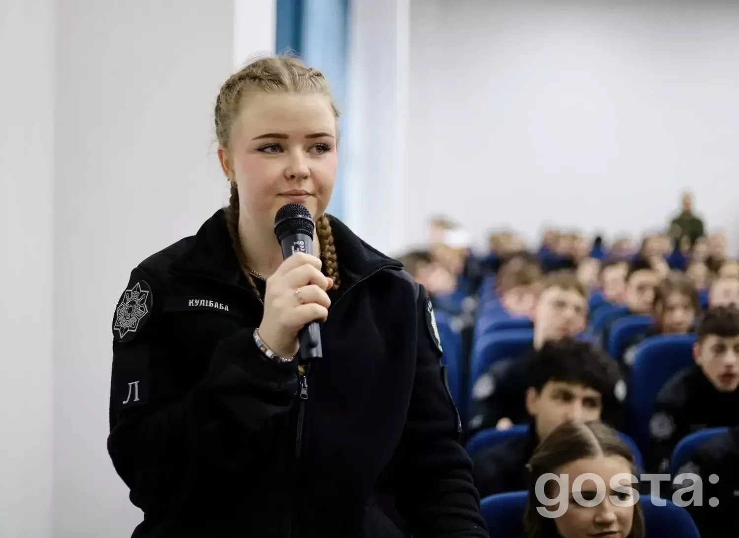 На фото дівчина з мікрофоном виступає перед аудиторією ліцеїстів МВС в Івано-Франківську.