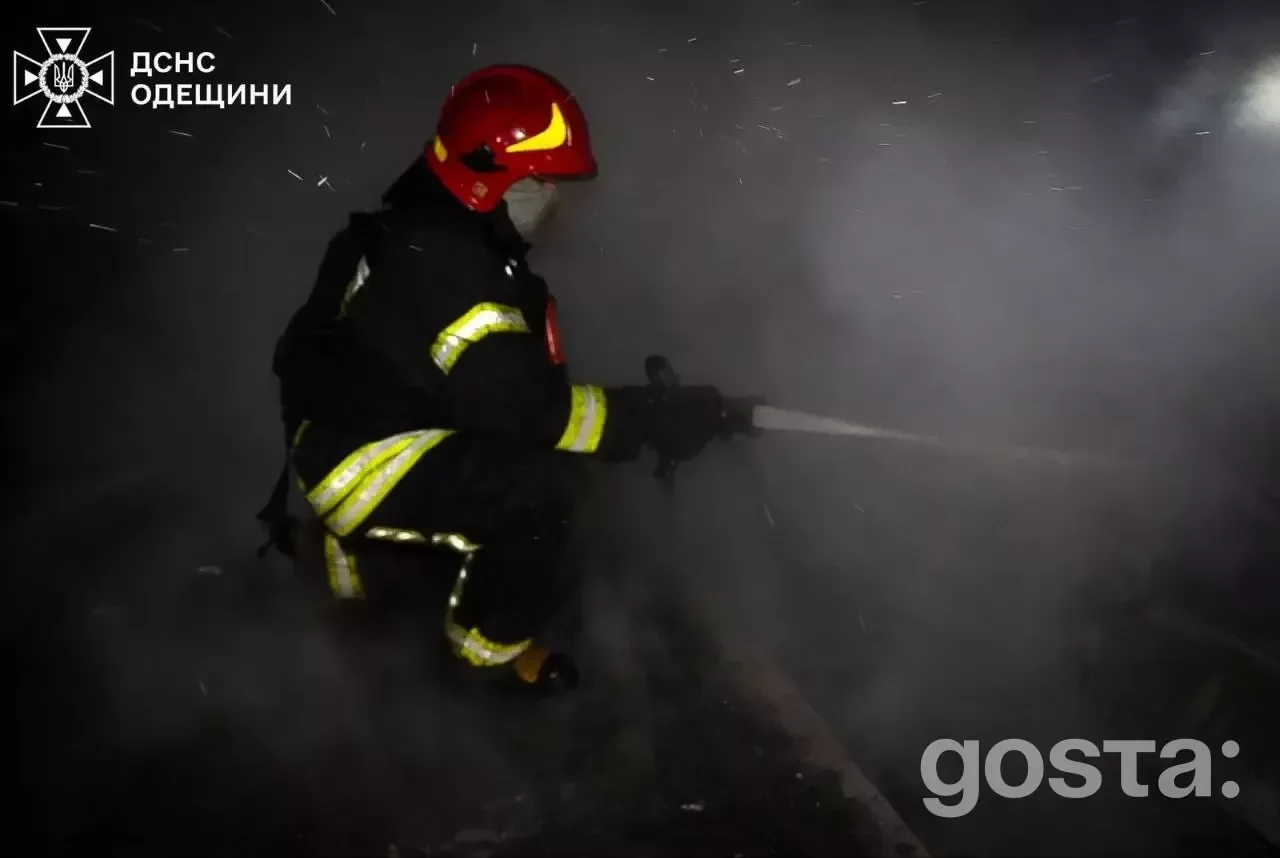 Рятувальник гасить пожежу після обстрілу, густий дим заповнює повітря, видимі пошкодження інфраструктури.