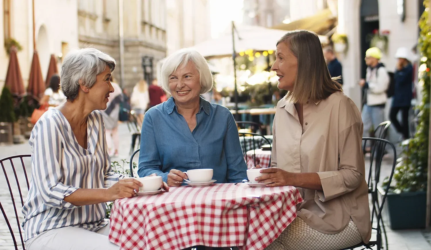 Three women enjoying coffee together on a café terrace