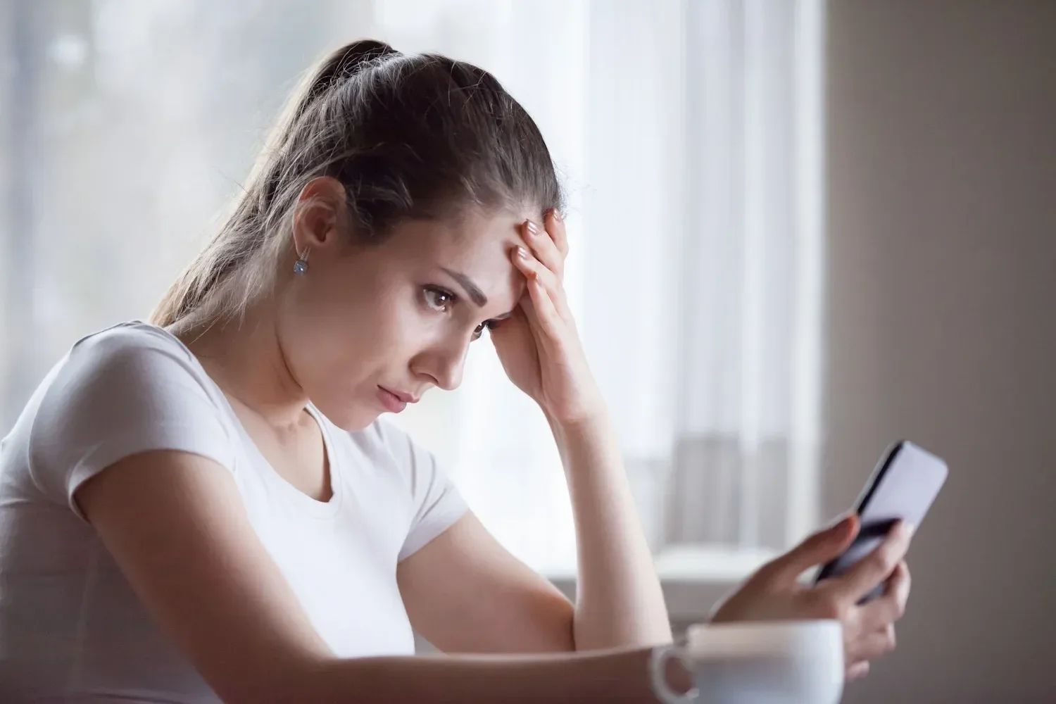 Woman anxiously checks her phone, worried about deceptive messages